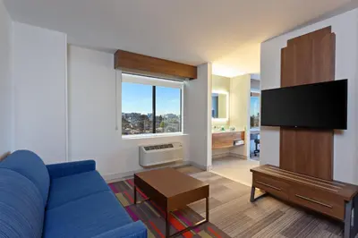 a living room with a blue couch and a flat screen tv at Holiday Inn Express Los Angeles LAX Airport by IHG in Los Angeles