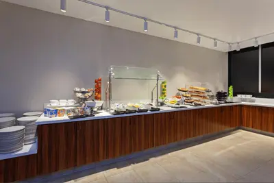 a buffet line in a restaurant with plates of food at Holiday Inn Los Angeles - LAX Airport by IHG in Los Angeles
