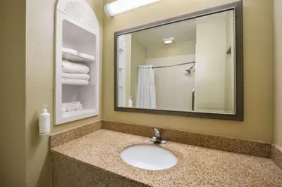 a bathroom with a sink and a mirror at Hotel Marguerite South Anaheim - Garden Grove, Trademark Collection by Wyndham in Anaheim