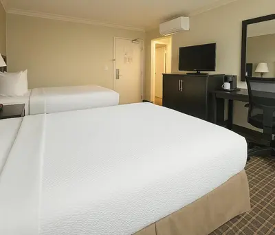 a hotel room with two beds and a desk and a television at The Live Hotel in Los Angeles