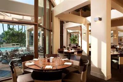 a restaurant with tables and chairs and a pool at Hyatt Regency Long Beach in Long Beach