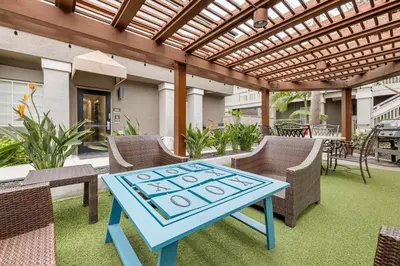 a blue table and chairs on a patio with a pergola at Sonesta ES Suites Torrance Redondo Beach in Torrance