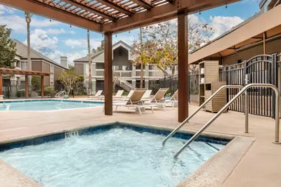 a swimming pool with a deck and chairs next to a building at Sonesta ES Suites Torrance Redondo Beach in Torrance
