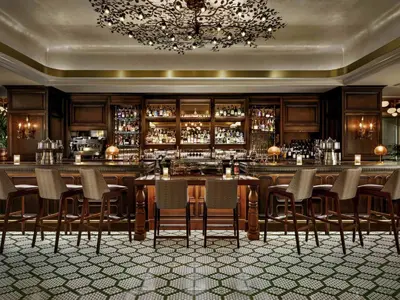 a restaurant with a bar with chairs and a chandelier at Fairmont Century Plaza Los Angeles at Beverly Hills in Los Angeles