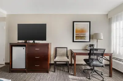 a room with a desk with a television and chairs at Best Western Plus Carriage Inn in Sherman Oaks