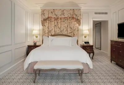 a bedroom with a large white bed and a tv at The Peninsula Beverly Hills in Los Angeles