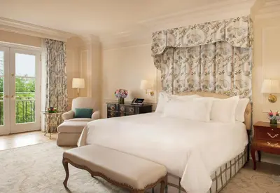 a bedroom with a large white bed and a chair at The Peninsula Beverly Hills in Los Angeles