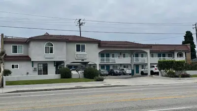 a large building with cars parked in a parking lot at El Segundo Inn in Hawthorne