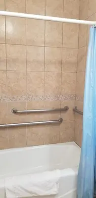a shower with a blue shower curtain and a tub at Royal Inn Motel Long Beach in Long Beach