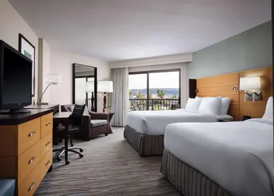 a hotel room with two beds and a desk and a television at Sonesta Redondo Beach and Marina in Redondo Beach