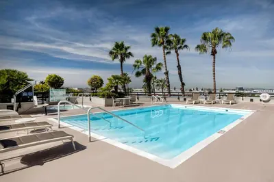 a swimming pool with chairs and palm trees at Holiday Inn Los Angeles Gateway-Torrance by IHG in Torrance