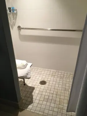 a bathroom with a shower and a white tiled floor at Crowne Plaza Ventura Beach by IHG in Ventura