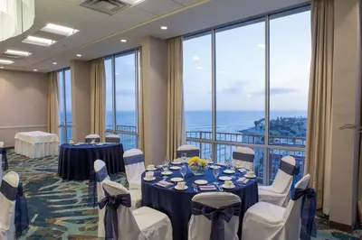 a conference room with tables and chairs and large windows at Crowne Plaza Ventura Beach by IHG in Ventura