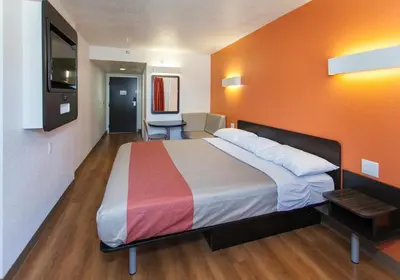 a bedroom with a large bed with an orange wall at Motel 6-Los Angeles, CA - Los Angeles - LAX in Inglewood