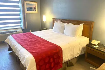 a hotel room with a bed with a red and white blanket at Ramada by Wyndham Los Angeles/Wilshire Center in Los Angeles