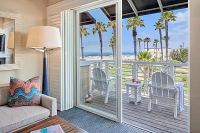 a living room with a balcony with palm trees at Beach House Hotel at Hermosa Beach in Hermosa Beach