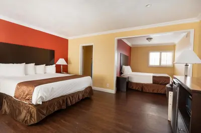 a hotel room with two beds and orange walls at Americas Best Value Inn & Suites Anaheim in Anaheim