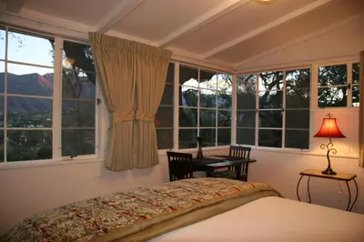 a bedroom with windows and a bed and a table at Ojai Retreat & Inn in Ojai