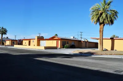 an empty street with a palm tree and buildings at A Nights Inn in Ridgecrest