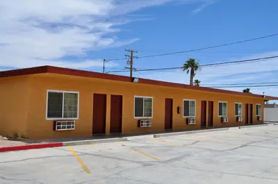 an orange building with a palm tree in front of it at A Nights Inn in Ridgecrest
