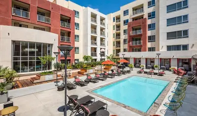 an apartment patio with a pool and chairs and buildings at Hollywood Panoramic Views, Pool, Gym & Free parking! in Los Angeles