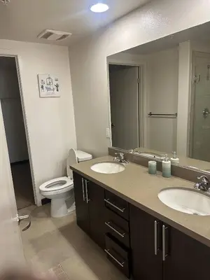 a bathroom with two sinks and a toilet and a mirror at Hollywood Panoramic Views, Pool, Gym & Free parking! in Los Angeles