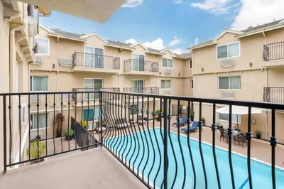 an apartment balcony with a swimming pool in front of a building at Comfort Inn Cockatoo Near LAX Airport in Hawthorne