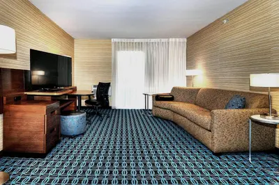 a hotel room with a couch and a desk and a television at Fairfield Inn & Suites by Marriott Los Angeles Rosemead in Rosemead