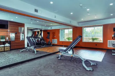 a gym with three chairs in a room with orange walls at Fairfield Inn & Suites by Marriott Los Angeles Rosemead in Rosemead