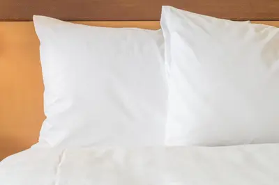 a bed with white sheets and pillows on it at Holiday Inn & Suites Bakersfield by IHG in Bakersfield