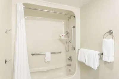 a bathroom with a tub and a shower with towels at Baymont by Wyndham Barstow Historic Route 66 in Barstow