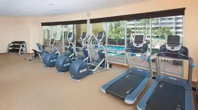 a gym with a row of tread machines and a pool at Hilton Garden Inn Burbank Los Angeles in Burbank