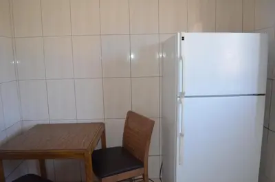 a kitchen with a table and a white refrigerator at Seaside Inn Motel in Port Hueneme
