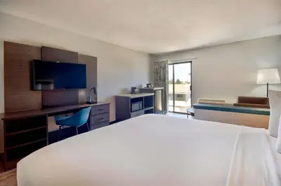 a hotel room with a large white bed and a desk at Studio 6 Suites Lawndale, CA South Bay in Lawndale