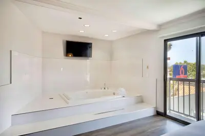 a white bathroom with a tub and a tv at Studio 6 Suites Lawndale, CA South Bay in Lawndale