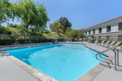 a large swimming pool with chairs and a building at Best Western Valencia/Six Flags Inn & Suites in Santa Clarita