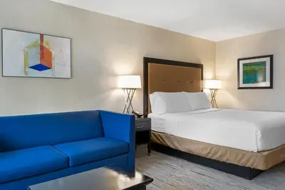 a hotel room with a bed and a blue couch at Holiday Inn Express San Bernardino Colton by IHG in Colton