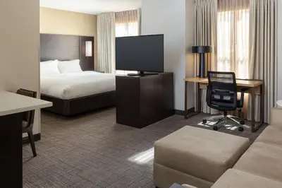 a hotel room with a bed and a desk with a television at Residence Inn by Marriott Corona Riverside in Corona