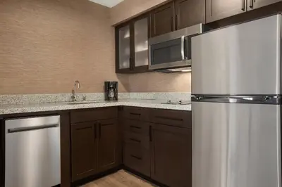a kitchen with wooden cabinets and a stainless steel refrigerator at Residence Inn by Marriott Palmdale Lancaster in Palmdale