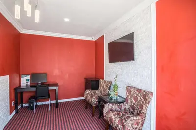 a room with a red wall with a chair and a desk at El Dorado Inn in Lynwood