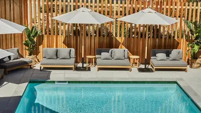 a swimming pool with two chairs and umbrellas next to a pool at Hotel June Malibu in Malibu