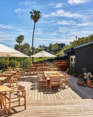 a patio with tables and umbrellas on a deck at Hotel June Malibu in Malibu