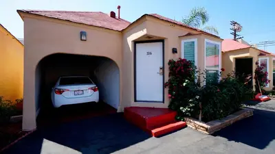 a car is parked in a garage next to a house at El Royale Hotel - Near Universal Studios Hollywood in Los Angeles