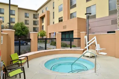 a hot tub in a patio with chairs and a building at SpringHill Suites by Marriott Corona Riverside in Corona
