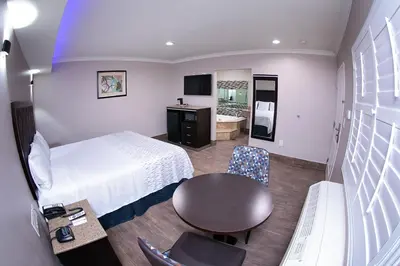 a hotel room with a bed and a table and chair at Diamond Bell Inn & Suites in Bell