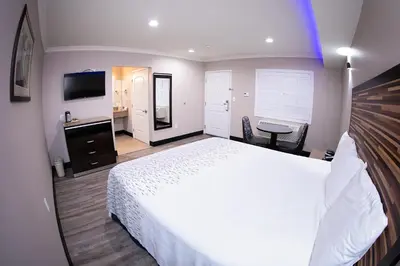 a bedroom with a large white bed and a desk at Diamond Bell Inn & Suites in Bell