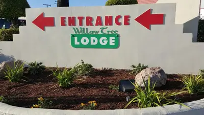 a sign for an entrance to a wild tree lodge at Willow Tree Lodge in Fullerton