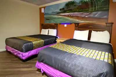 two beds in a room with a painting on the wall at Robinhood Motel Anaheim West in Anaheim