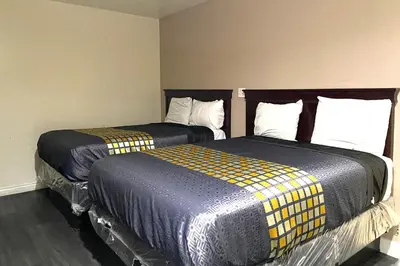 two beds sitting next to each other in a room at Robinhood Motel Anaheim West in Anaheim