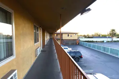 a balcony of a building with a car parked in a parking lot at Robinhood Motel Anaheim West in Anaheim